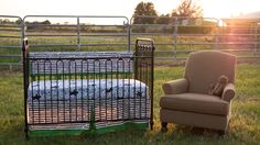 a baby crib next to a chair in the grass with a teddy bear on it