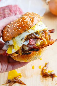 a hand holding a sandwich with meat and cheese