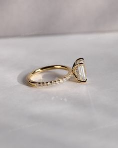 a yellow gold engagement ring with an oval cut diamond in the center and side stones around the band