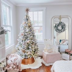 a white christmas tree in a living room next to a mirror and other holiday decorations