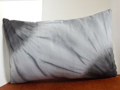 a black and white pillow sitting on top of a wooden table next to a wall