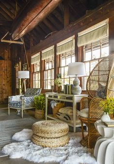 a living room with wicker furniture and large windows on the wall, along with white fluffy rugs