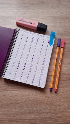 two pencils and a notebook on a table