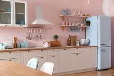 a kitchen with pink walls and white cabinets