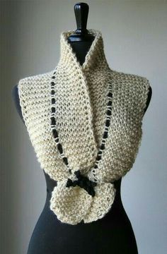 a crocheted scarf on a mannequin with a black and white bow