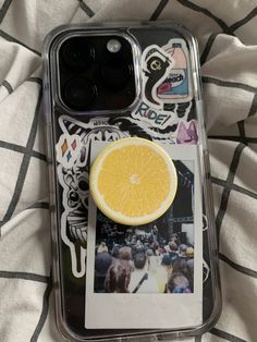 an orange slice sitting on top of a cell phone case with stickers around it