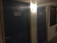 two blue doors with numbers on them in a hallway