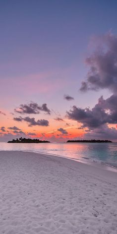 the sun is setting on an empty beach