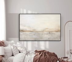 a large painting hanging on the wall above a bed in a room with white walls