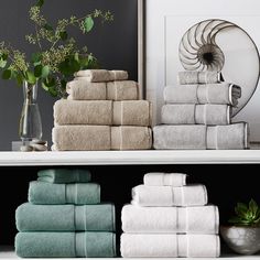 towels are stacked on top of each other in front of a black wall and white shelves