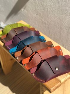 several different colors of leather sitting on top of a wooden table next to a white wall