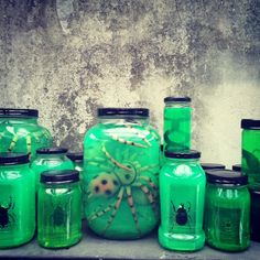 green jars with bugs on them are sitting next to each other in front of a concrete wall