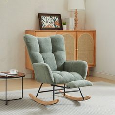 a rocking chair in a living room next to a coffee table and side table with a lamp on it