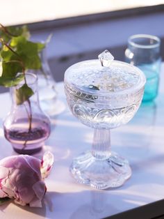 flowers and vases sitting on a table with water in the glass bowl next to them