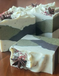 four soap bars sitting on top of a wooden table covered in white and green frosting