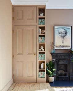 a living room with an open bookcase next to a fireplace and potted plant