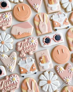 many decorated cookies are arranged on a white surface with pink and yellow accents, such as daisies