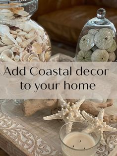 two glass vases filled with shells and seashells on top of a wooden tray