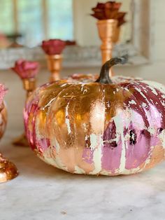 a painted pumpkin sitting on top of a table next to other decorative items and candles