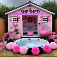 a hot tub in front of a pink shed with flamingos around it and decorations on the outside