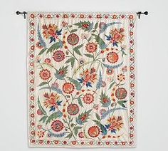 an embroidered wall hanging with flowers and leaves on the outside, in front of a white background