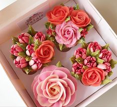 four cupcakes in a box decorated with pink and orange flowers