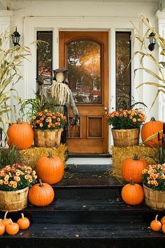 pumpkins and hay bales in front of a door with scarecrow on it