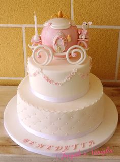 there is a white cake with pink decorations on the top and bottom tiers that are decorated like a horse drawn carriage