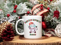 a white coffee mug with santa's favorite phrases on it sitting in front of christmas decorations