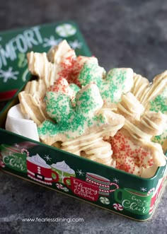 a tin filled with white and green christmas cookies next to a box of peppermint shortbreads