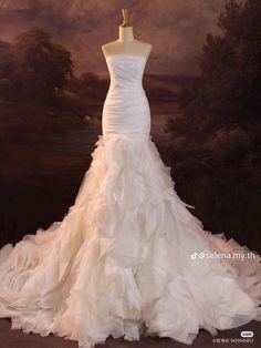 a white wedding dress is displayed on a mannequin stand in front of a painting