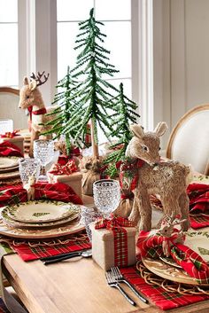 a christmas table setting with red and green napkins, silverware and deer figurines