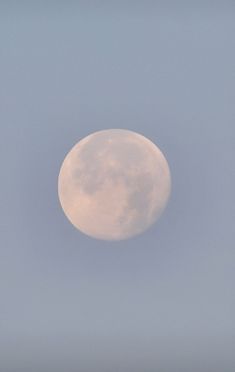 an airplane flying in the sky with a large white moon behind it's back