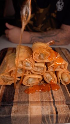 some kind of food that is on a cutting board and being drizzled with sauce