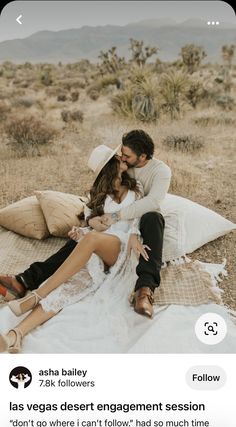 a man and woman sitting on a blanket in the desert