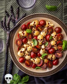 a plate filled with tomatoes and skulls on top of a table next to silverware