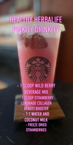 a pink drink in a cup on top of a wooden table with information about the drinks