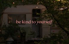 an rv with the words be kind to yourself written on it in front of trees