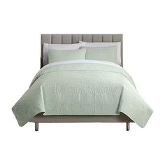 a bed with a green comforter and pillows