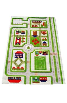 a green and white rug with houses, cars, and soccer fields on the ground