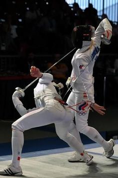 two people in white fencing suits playing with each other