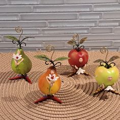 four small figurines are arranged in the shape of apples and pears on a mat