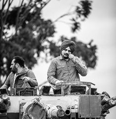 two men sitting on top of an armored vehicle