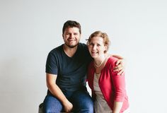 a man and woman are sitting on a bench smiling at the camera while posing for a photo