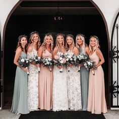 a group of women standing next to each other in front of a doorway holding bouquets