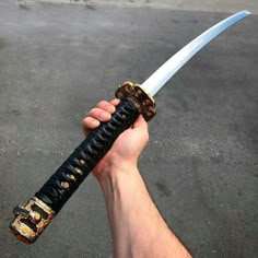 a hand holding a black and gold colored knife