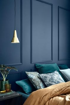 a bedroom with blue walls, gold bedding and a plant on the side table