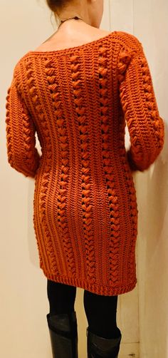 a woman in an orange sweater and black boots is looking at the back of her jacket