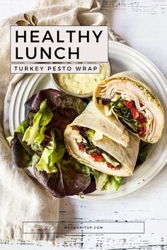 a healthy lunch with turkey pesto wrap on a white plate next to a bowl of ranch dressing