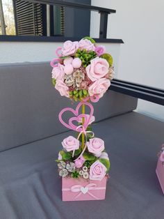 a pink flower arrangement in a box on top of a table with other flowers and decorations